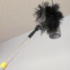 Dusting a hanging light fixture.