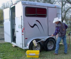 Cleaning the tires of a horse trailer with the stiff bi-level brush.