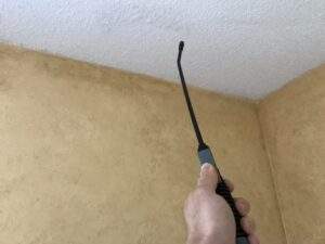 Wetting down the popcorn ceiling with a pump sprayer prior to scraping.