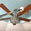 Dusting a ceiling fan with a lambs wool duster.