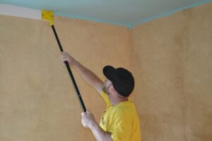Edging the wall near the ceiling with a paint edger.
