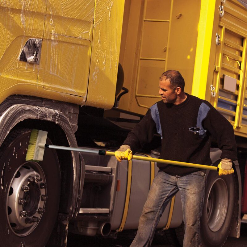 Cleaning giant dump truck wheels with stiff scrub brush.