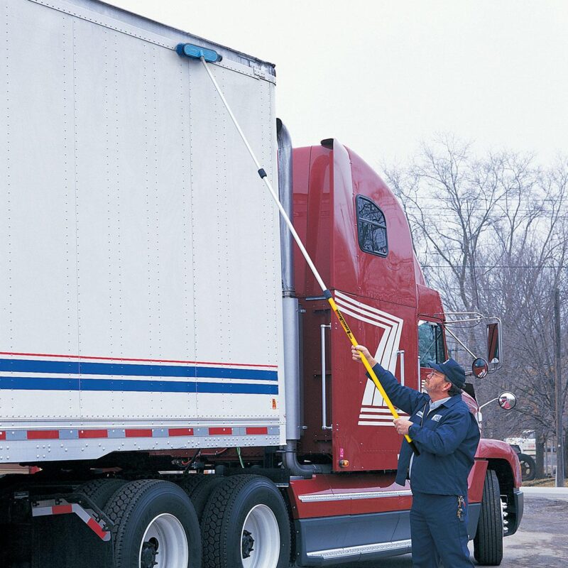 Cleaning a truck with a brush and 3-section extension pole.