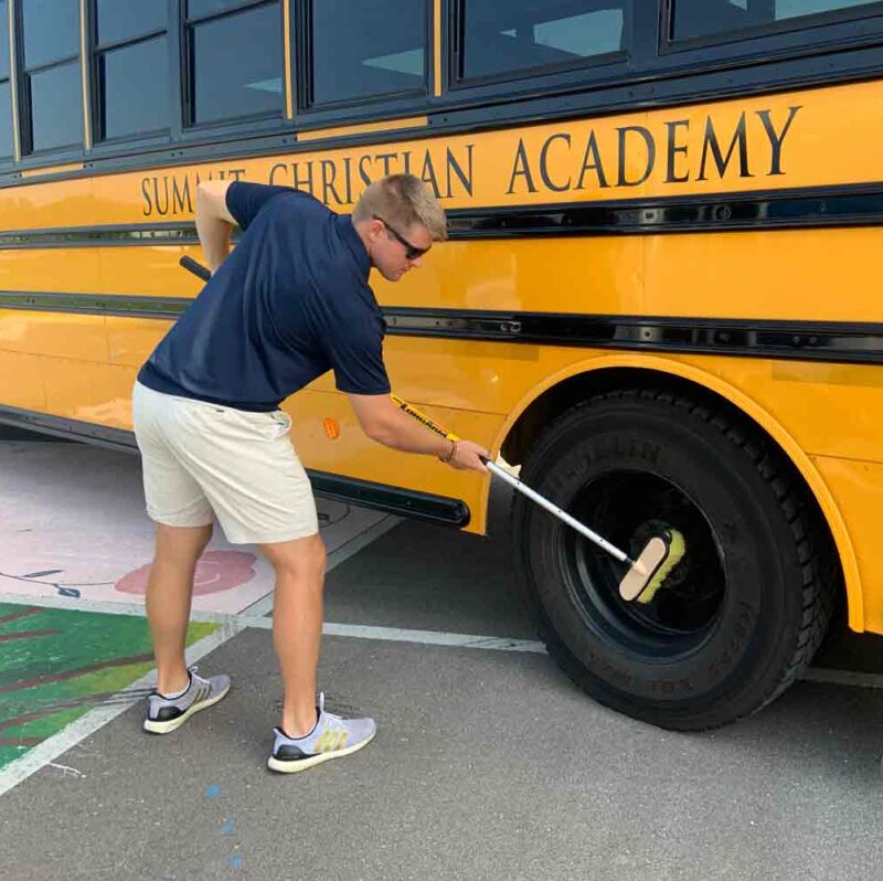 Super Tab-Lok extension pole cleaning the wheels on a school bus.