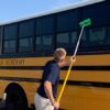 Cleaning a school bus with a brush.