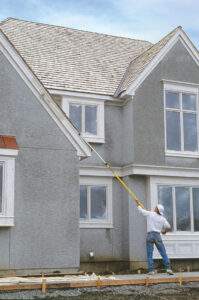 Painting trim on a home with a 3-section extension pole and a small roller.