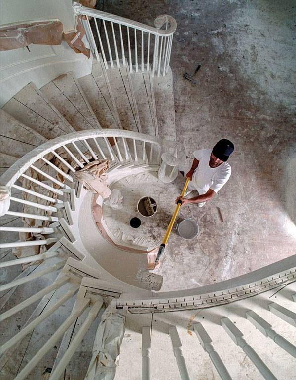 Man painting a staircase with an extension pole