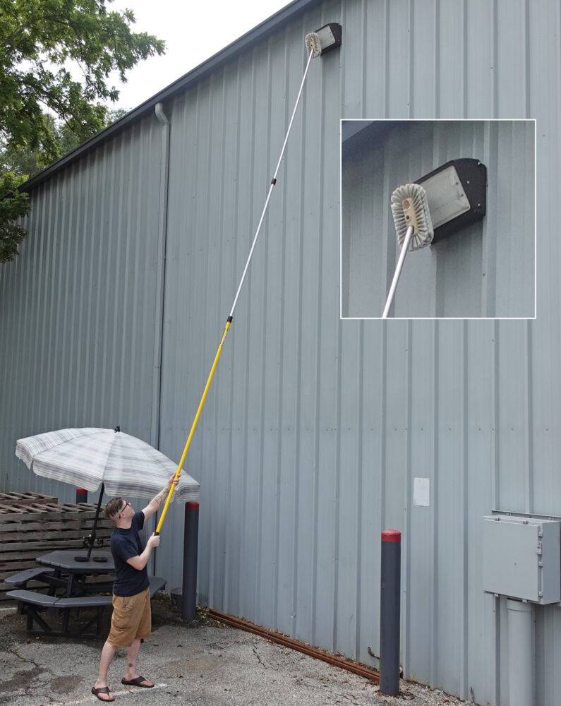 Technician using an extension pole with a cobweb brush